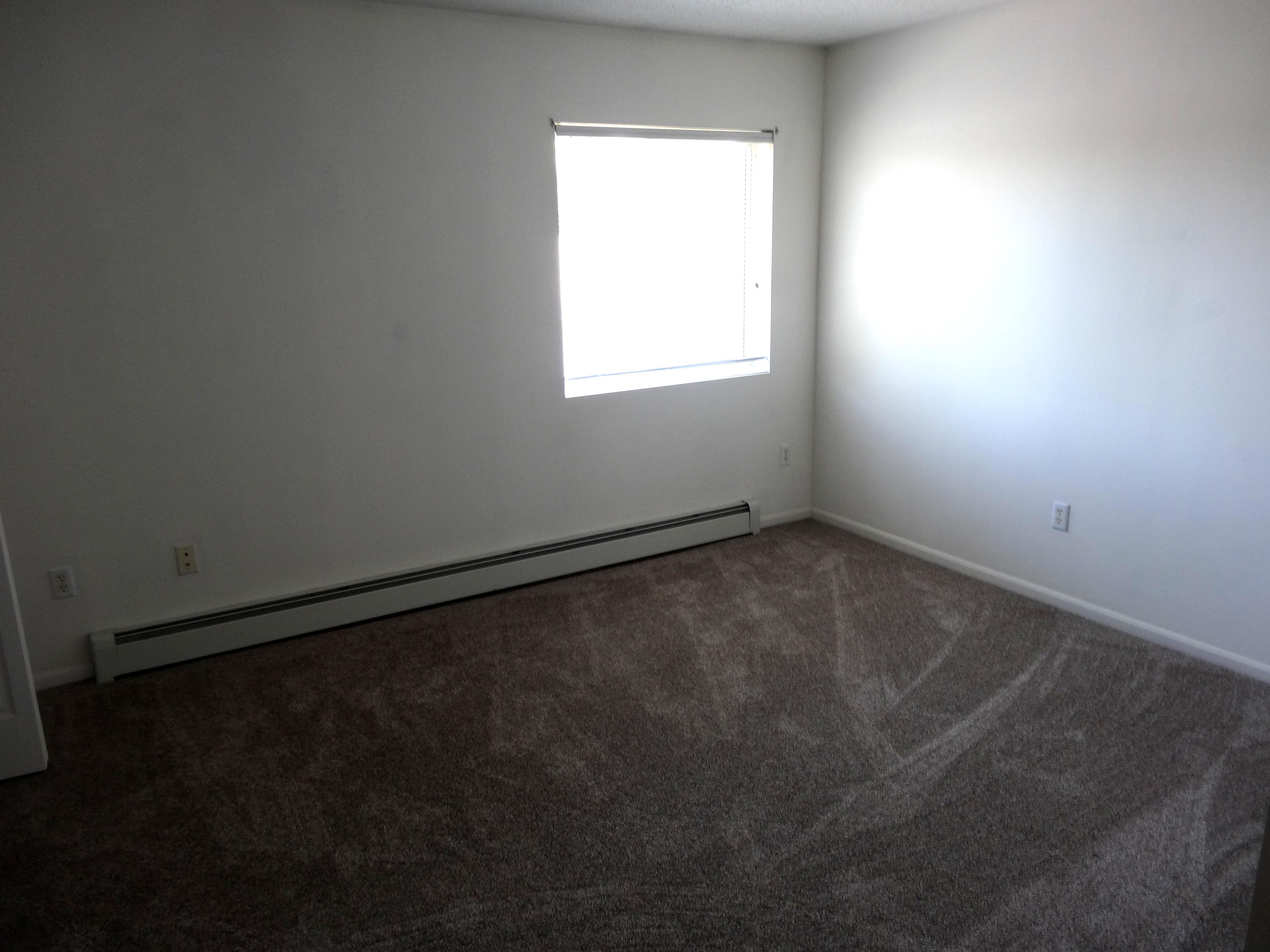 diagonal-view-of-2nd-bedroom-carpeted-with-window