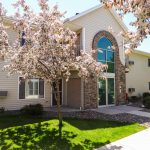 apartment-building-entry-door-with-green-grass-and-flowering-trees-medford-wi