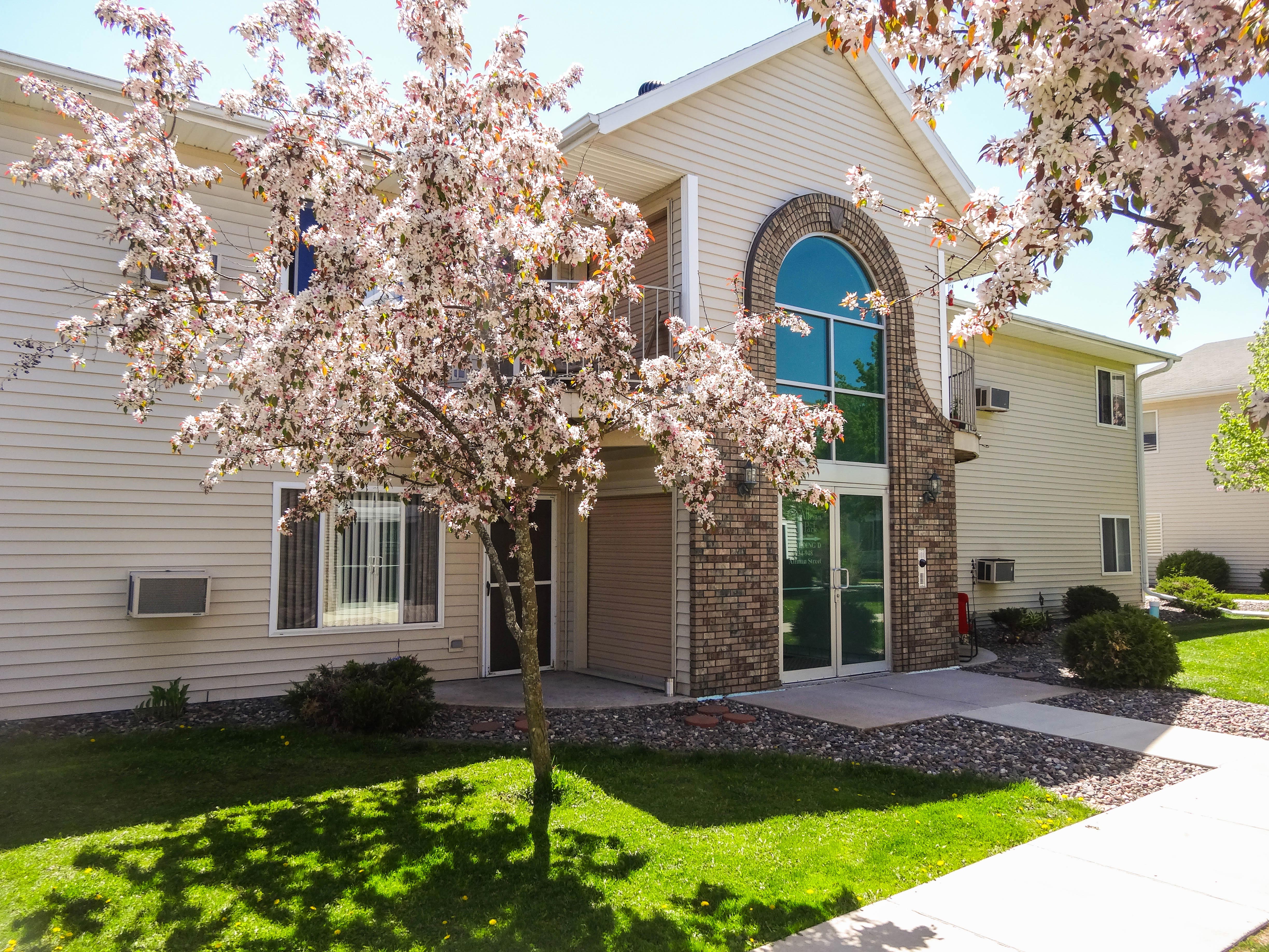 apartment-building-entry-door-with-green-grass-and-flowering-trees-medford-wi