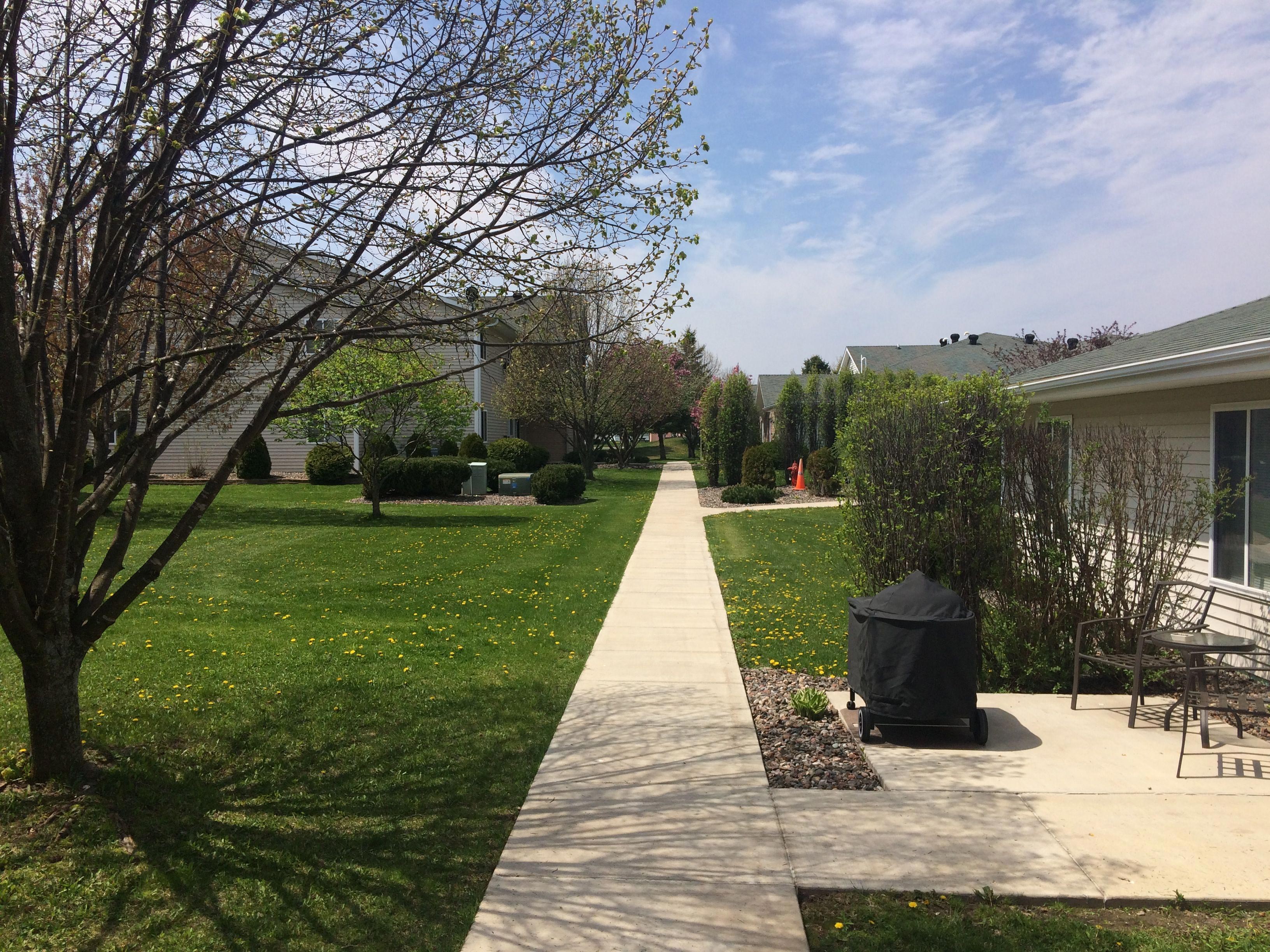 concrete-sidewalk-between-condo-and-apartment-building-green-grass-all-around